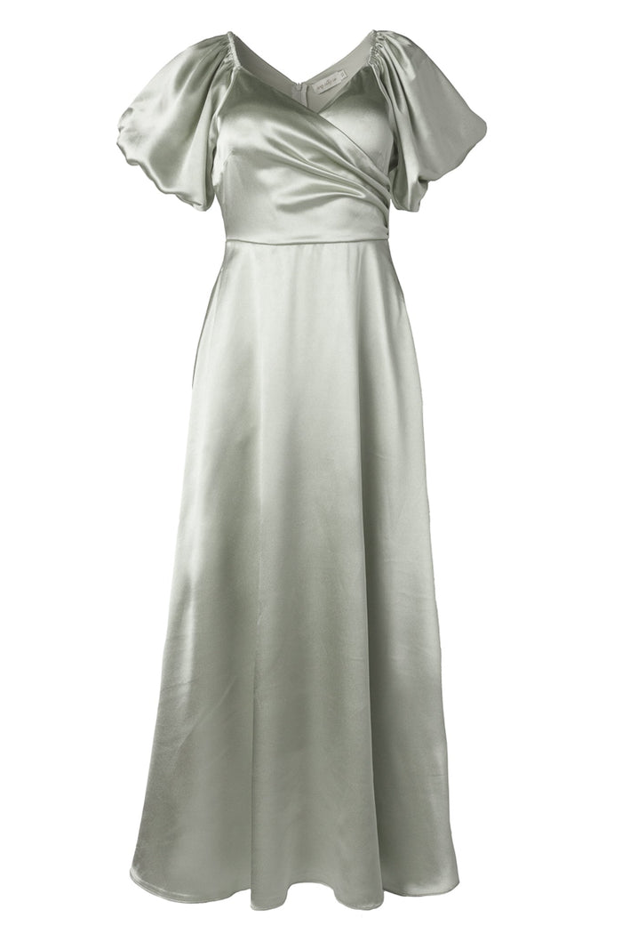 The Tessie Dress in Sage by Ivy City Co features a light green satin fabric with short puff sleeves, a V-neckline, and a fitted waist. Its wrap-style bodice and flowing, ankle-length skirt create an elegant bridesmaid dress that is both timeless and flattering.
