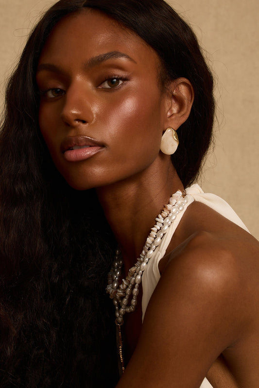 Model wearing the 12th Tribe White Sands Stone Earrings, bold white and gold chunky stone drop earrings with a push back closure for an effortlessly elevated statement look. Perfect for accessorizing your favorite vacation maxi dress, beach vacation outfit, or summer night out.